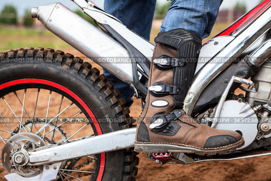 Close up view at rider's motocross boot standing on peg of dirt motorcycle. Safety apparel for riding. Стоковое фото, фотограф Кекяляйнен Андрей / Фотобанк Лори
