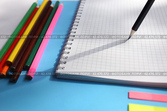 Close up view notebooks, pencils, on a blue background. Back to school concept. Office supplies flat lay. Стоковое фото, фотограф Александра Баранова / Фотобанк Лори