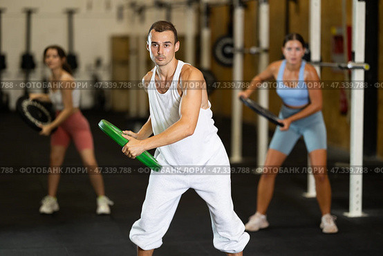 Closeup of athletic sports man standing with plate of barbell in hands in fitness studio. Стоковое фото, фотограф Яков Филимонов / Фотобанк Лори
