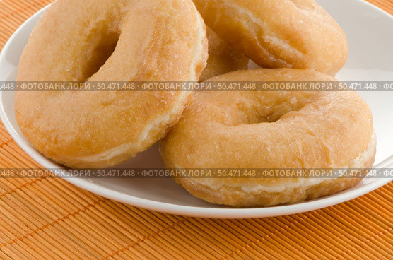 Closeup of donuts on a plate on orange straw mat background. Стоковое фото, агентство Ingram Publishing / Фотобанк Лори