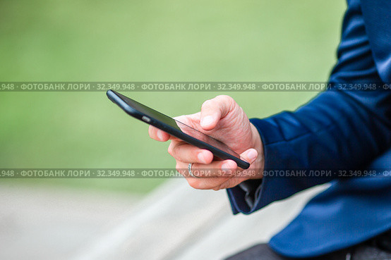 Closeup of male hands is holding cellphone outdoors on the street. Man using mobile smartphone. Стоковое фото, фотограф Дмитрий Травников / Фотобанк Лори
