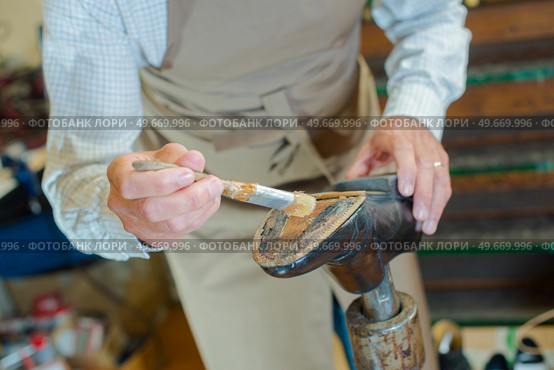 Cobbler painting glue on to sole of shoe. Стоковое фото, агентство Ingram Publishing / Фотобанк Лори