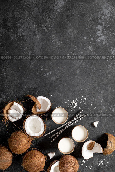 Coconut milk, whole and cracked coconuts on black background, top view. Стоковое фото, агентство Ingram Publishing / Фотобанк Лори