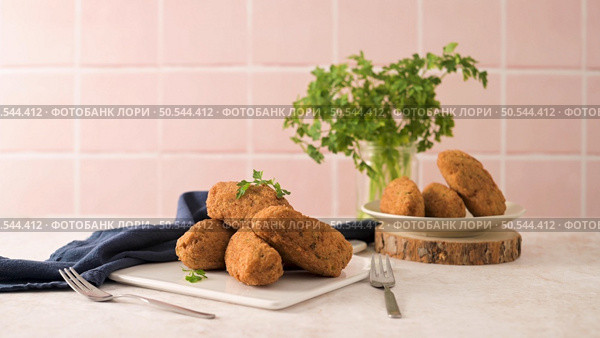 Cod dumplings, or "bolinhos de bacalhau" and parsley leaves on white ceramic dishes in a kitchen counter top. Стоковое фото, агентство Ingram Publishing / Фотобанк Лори