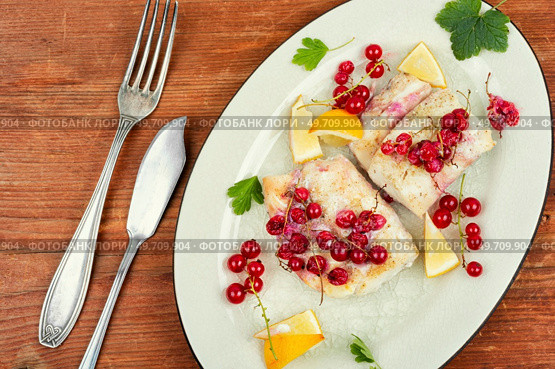 Cod fillet without skin cooking with red currants. Cod fish, white fish on wooden table.. Codfish loin baked with berries. Стоковое фото, агентство Ingram Publishing / Фотобанк Лори
