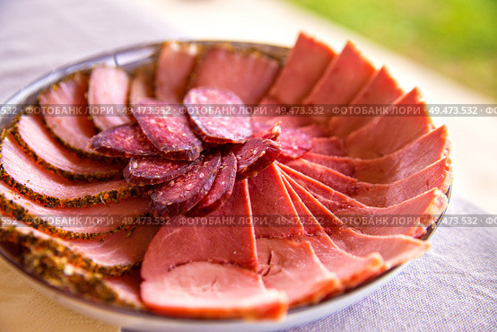 Cold smoked meat plate with sliced prosciutto, salami, bacon, pork chops. Different kinds of meat cuts on the boards. Meat antipasto platter. Traditional Belorussian cuisine. Стоковое фото, агентство Ingram Publishing / Фотобанк Лори