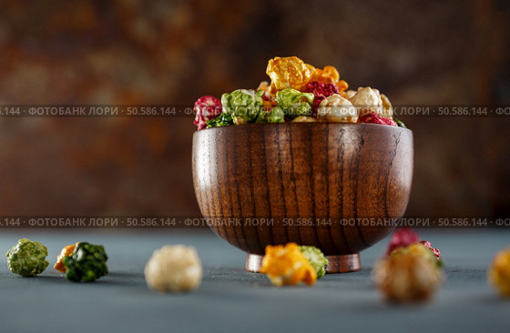 Colored popcorn in wooden bowl. Shallow DOF. Colored popcorn in wooden bowl. Стоковое фото, агентство Ingram Publishing / Фотобанк Лори