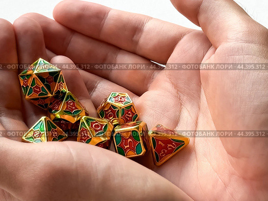 Colorful dungeons and dragons dice set held in hands for tabletop gaming enthusiasts. Стоковое фото, фотограф Lamina Akulova / Фотобанк Лори
