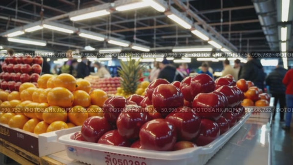 Colorful fruits filling white market trays, showcasing ripe red apples and vibrant oranges against busy produce display highlighting freshness and seasonal abundance. Стоковое AI-видео, аниматор Данил Руденко / Фотобанк Лори