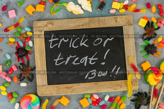 Colorful halloween candies on stone. Trick and treat letters on blackboard with colorful halloween candies on stone with copy space. Стоковое фото, агентство Ingram Publishing / Фотобанк Лори