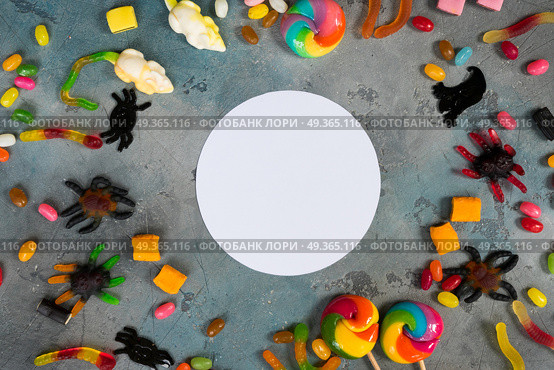 Colorful halloween candies on stone. Trick and treat - colorful halloween candies flat lay scene on stone with copy space on white circle. Стоковое фото, агентство Ingram Publishing / Фотобанк Лори