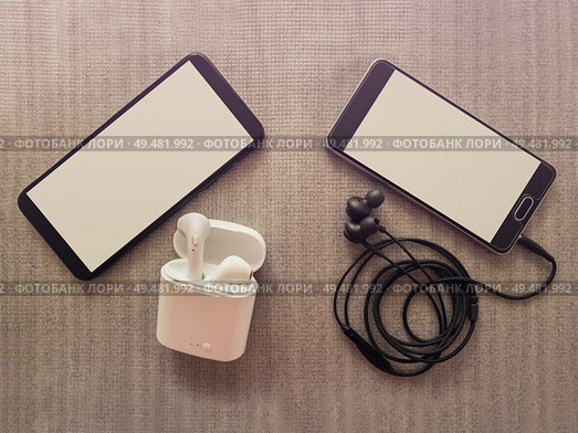 Comparison between two phones, one has 3.5mm jack wired headphones vs wireless earphones for music listening. Pros and cons, opposite contrary. Technology development tendencies, entertainment concept. Стоковое фото, агентство Ingram Publishing / Фотобанк Лори