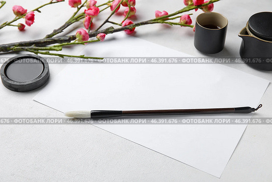 Composition with blank sheet of paper, ink, brush, cup of tea and blooming branch on light background. International Haiku Poetry Day. Стоковое фото, фотограф Pixel_shot / Фотобанк Лори