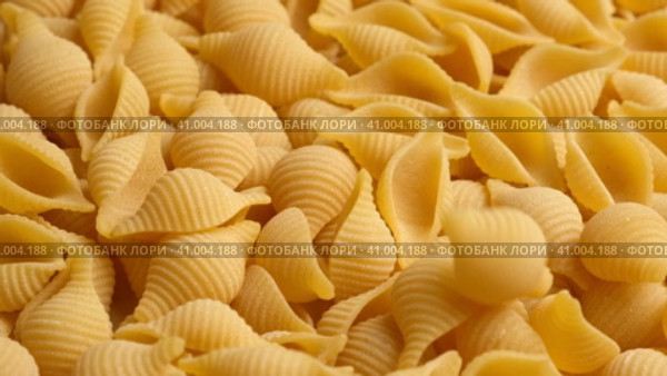 Conchiglie, Shells or Seashells Pasta Wallpaper. Spiral Raw Macaroni from Wheat flour rotating on Turntable. Close Up Top View. Uncooked Pasta Spinning. Full Frame. Food Background. Conchigliette. Стоковое видео, видеограф Марина Демидюк / Фотобанк Лори