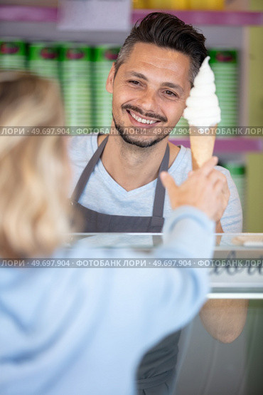 confectioner selling ice cream to young woman in the shop. Стоковое фото, агентство Ingram Publishing / Фотобанк Лори
