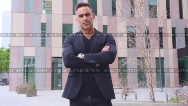 Confident businessman standing with arms crossed in urban setting.Vertical. Стоковое видео, видеограф Raquel Corcoles Mendez / Фотобанк Лори