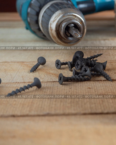 Construction and repair, Home working tool- self-tapping screws on the background of a screwdriver on wooden boards. Self-tapping screws on a wooden background. Стоковое фото, фотограф Александр Кротков / Фотобанк Лори