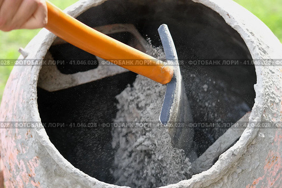 Construction site. Adding lime, sand and stones to rotating cement mixer. Builder working with shovel during concrete solution mortar preparation. Bricklayer job machine equipment. Cement slurry. Стоковое фото, фотограф Марина Демидюк / Фотобанк Лори