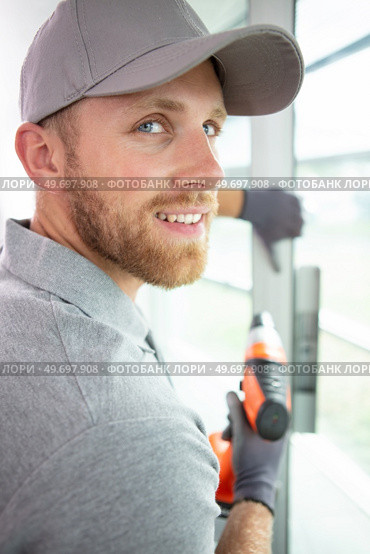 construction worker using drill to install window. Стоковое фото, агентство Ingram Publishing / Фотобанк Лори