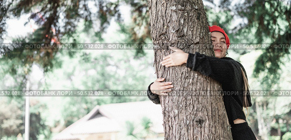 Contented young woman hugging a large tree with a blissful expression with copy space. Concept of care for environment. Стоковое фото, агентство Ingram Publishing / Фотобанк Лори