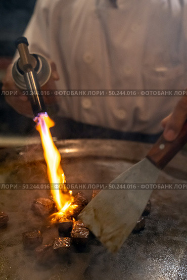 Cooking of beef teppanyaki recipe japanese grilled beef on cooking pan with scraper and gas burner flame. Стоковое фото, агентство Ingram Publishing / Фотобанк Лори
