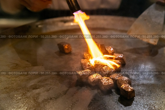 Cooking of beef teppanyaki recipe japanese grilled beef on cooking pan with scraper and gas burner flame. Стоковое фото, агентство Ingram Publishing / Фотобанк Лори