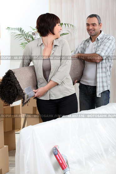 Couple carrying rolled-up carpet. Стоковое фото, агентство Ingram Publishing / Фотобанк Лори