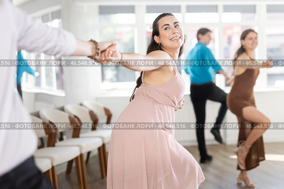 Couple in evening dresses enjoys pair dance boogie-woogie, interacting with each other on floor. Стоковое фото, фотограф Яков Филимонов / Фотобанк Лори