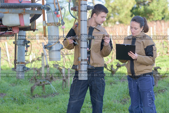couple of agricultors inspecting machinery before harvesting. Стоковое фото, агентство Ingram Publishing / Фотобанк Лори