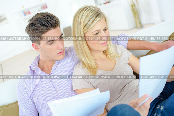 Couple reading through a contract on the sofa. Стоковое фото, агентство Ingram Publishing / Фотобанк Лори