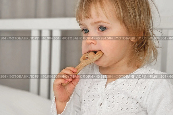 Cute baby girl playing tactile wooden and silicone toys. Young child hand plays sensory massage ball. Enhance the cognitive, physical process. Brain development. Teething toy. Dentition. Baby's teeth. Стоковое фото, фотограф Марина Демидюк / Фотобанк Лори