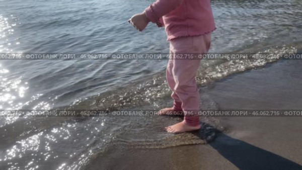 Cute baby girl playing with yellow sand and sea wave on beach shore pond. Стоковое видео, видеограф Spirit River / Фотобанк Лори
