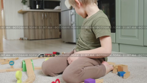 Cute little blonde child boy sitting on the floor playing with wooden toy train. Toddler kid plays railway. Made of natural materials. Birthday gift. Preschool employment. Brain, coordination exercise. Стоковое видео, видеограф Марина Демидюк / Фотобанк Лори