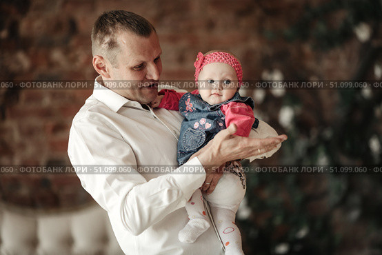 Dad Holds His Baby Daughter in His Arms Indoors at Home With Affection. Стоковое фото, фотограф Aleksandr Golubev / Фотобанк Лори