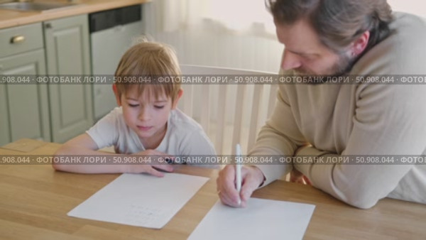 Dad teaches his son writing and counting. Kids primary education. Children learn, study in home school. Daddy male helping teaching little child boy support studying, learning homework. Knowledge day. Стоковое видео, видеограф Марина Демидюк / Фотобанк Лори