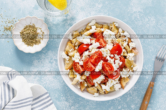 Dakos or koukouvagia salad. Classic recipe Cretan barley rusk salad with fresh tomato, mizithra cheese and oregano. Traditional mediterranean Greek cuisine. Healthy food, diet. Top view. Стоковое фото, агентство Ingram Publishing / Фотобанк Лори