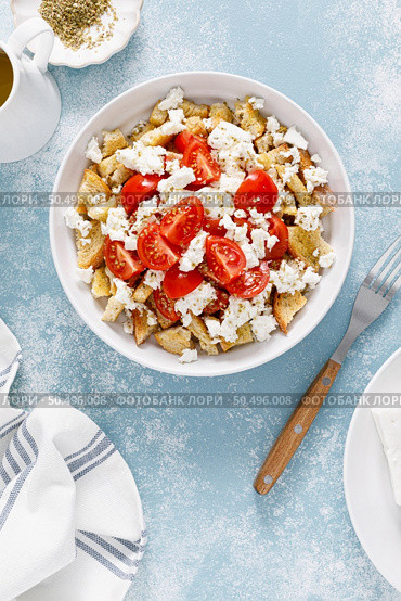 Dakos or koukouvagia salad. Classic recipe Cretan barley rusk salad with fresh tomato, mizithra cheese and oregano. Traditional mediterranean Greek cuisine. Healthy food, diet. Top view. Стоковое фото, агентство Ingram Publishing / Фотобанк Лори