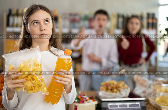 Daughter chose sweet drink and potato chips in store, and quarrels with parents over choice of food. Стоковое фото, фотограф Яков Филимонов / Фотобанк Лори
