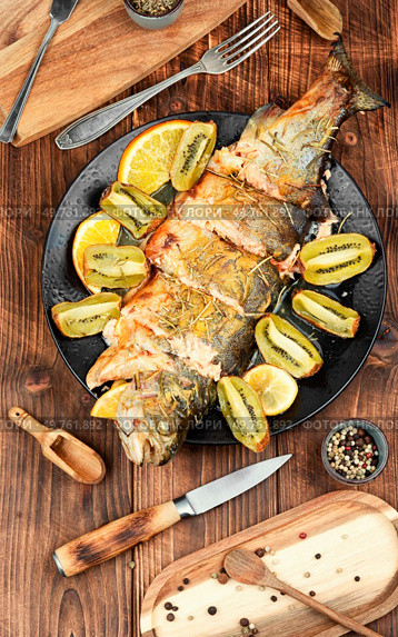 Delicious whole baked trout fish with kiwi fruit on a wooden table.. Whole baked trout fish. Стоковое фото, агентство Ingram Publishing / Фотобанк Лори