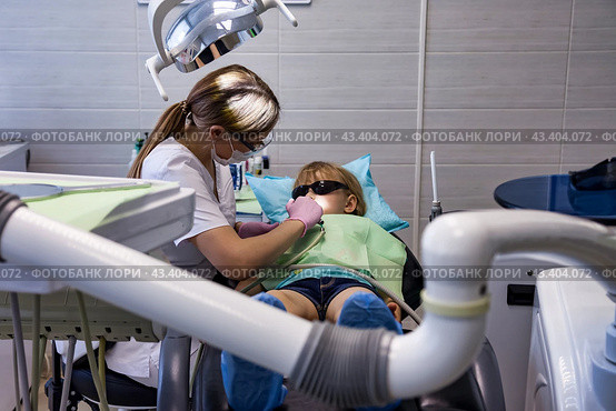 Dental office, woman dentist doing treating teeth little child 5 year old. Kid girl visit dentist doctor having treats teeth in clinic. Medical healthy children dentistry concept. Copy ad text space. Стоковое фото, фотограф Aleksandr Golubev / Фотобанк Лори