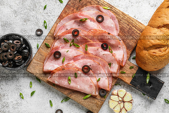 Деревянная доска с ломтиками вкусной ветчины, маслинами и хлебом на светлом фоне. Стоковое фото, фотограф Pixel_shot / Фотобанк Лори