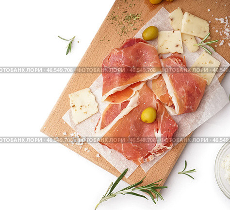 Деревянная доска с вкусными ломтиками хамона на светлом фоне. Стоковое фото, фотограф Pixel_shot / Фотобанк Лори