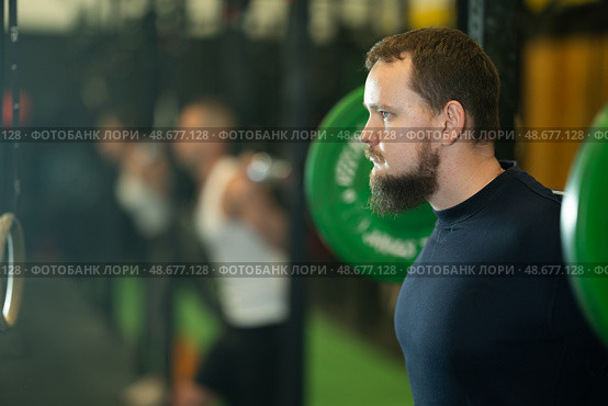 Determined young guy working out with weight rod during crossfit workout. Стоковое фото, фотограф Яков Филимонов / Фотобанк Лори