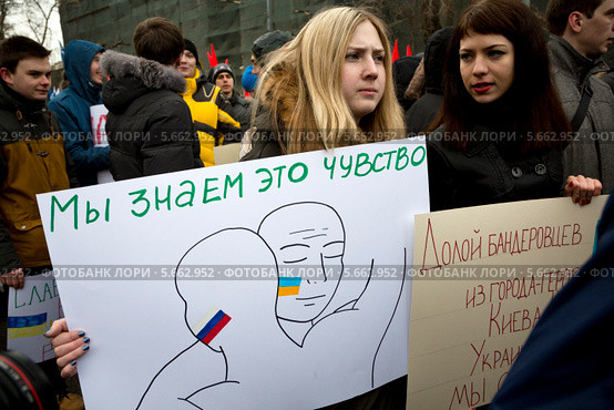 Девушка держит плакат, символизирующий друбу между Россией и Украиной, на шествии в поддержку соотечественников на Украине, Москва (2014 год). Редакционное фото, фотограф Николай Винокуров / Фотобанк Лори