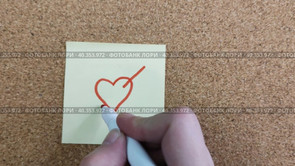 Девушка или парень рисует цветным фломастером сердце со стрелой на желтой бумажной наклейке. Красный маркер в женской или мужской руке. Стикер на пробковой доске для заметок. Рисунок на листе бумаги. Крупный план. A girl or a guy draws a heart with an arrow on a yellow paper sticker with a colored felt-tip pen. A red marker in a female or male hand. A sticker on a cork board for notes. Drawing on a piece of paper. Close-up. Стоковое видео, видеограф Ирина / Фотобанк Лори