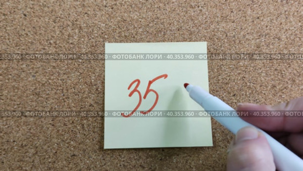 Девушка пишет надпись 35% красным маркером на желтом бумажном стикере, приклеенном к пробковой доске. Женская рука с цветным фломастером. Рукописный текст красивым почерком. Процент скидки, убытка или прибыли. Girl writes the inscription 35% with red marker on yellow paper sticker glued to cork board. Woman hand with colored felt-tip pen. Handwritten text in beautiful handwriting. Percentage of discount, loss or profit. Стоковое видео, видеограф Ирина / Фотобанк Лори