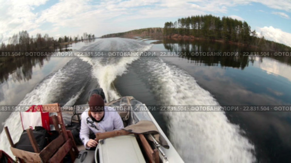 Девушка сидит на заднем сидении катера едущего по спокойной глади воды на озере. Стоковое видео, видеограф Кекяляйнен Андрей / Фотобанк Лори