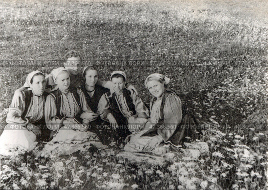 Девушки и юноша в русской народной одежде сидят на цветочном лугу, 1950-е гг. Стоковое фото, фотограф Retro / Фотобанк Лори
