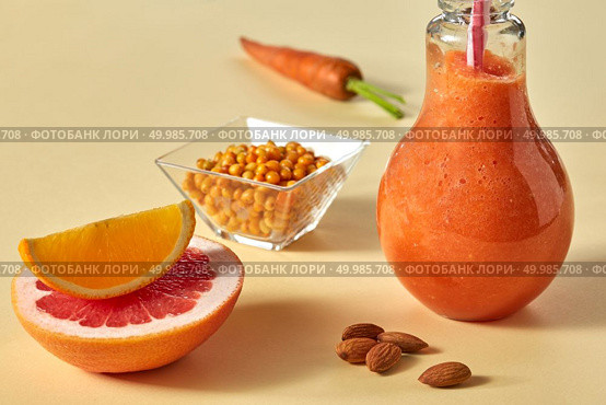 Dietary drink with carrots, grapefruit, orange, sea buckthorn and almonds in a glass on a yellow paper background. Healthy detox smoothies. Citrus vegetable smoothies with almonds and sea-buckthorn in a glass on a yellow paper background. Стоковое фото, агентство Ingram Publishing / Фотобанк Лори