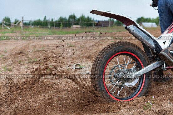 Dirt and sand fly from under rotating wheel of offroad motorcycle, action image, copy space. Стоковое фото, фотограф Кекяляйнен Андрей / Фотобанк Лори